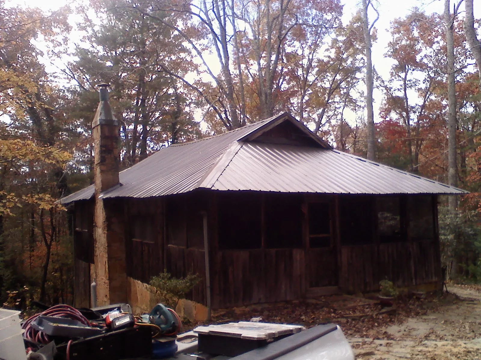 Brown metal hip roof on an old cabin with a stone chimney in Tuskegee Institute