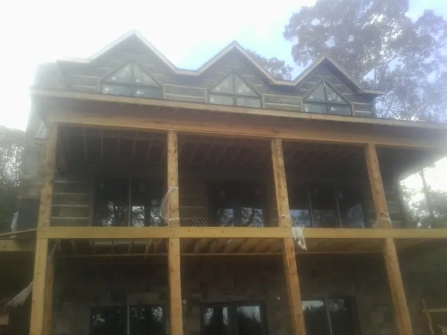 Dormers and porch framing on a large log home under construction — Roof Coating work by our crew in Tuskegee Institute