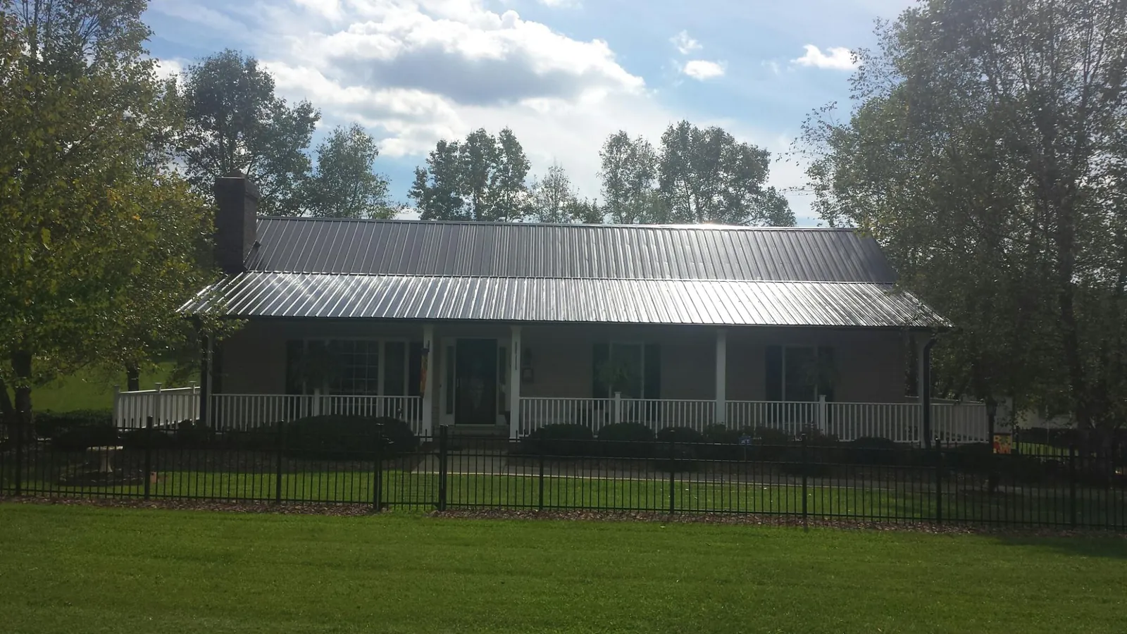 Gray metal roof on a brick ranch with a full width front porch — Gutter Guard Installation work by our crew in Tuskegee Institute