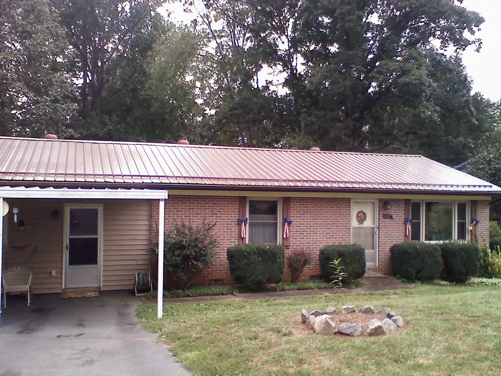 Bronze metal roof and carport on a brick ranch home — Roof Repair work by our crew in Tuskegee Institute