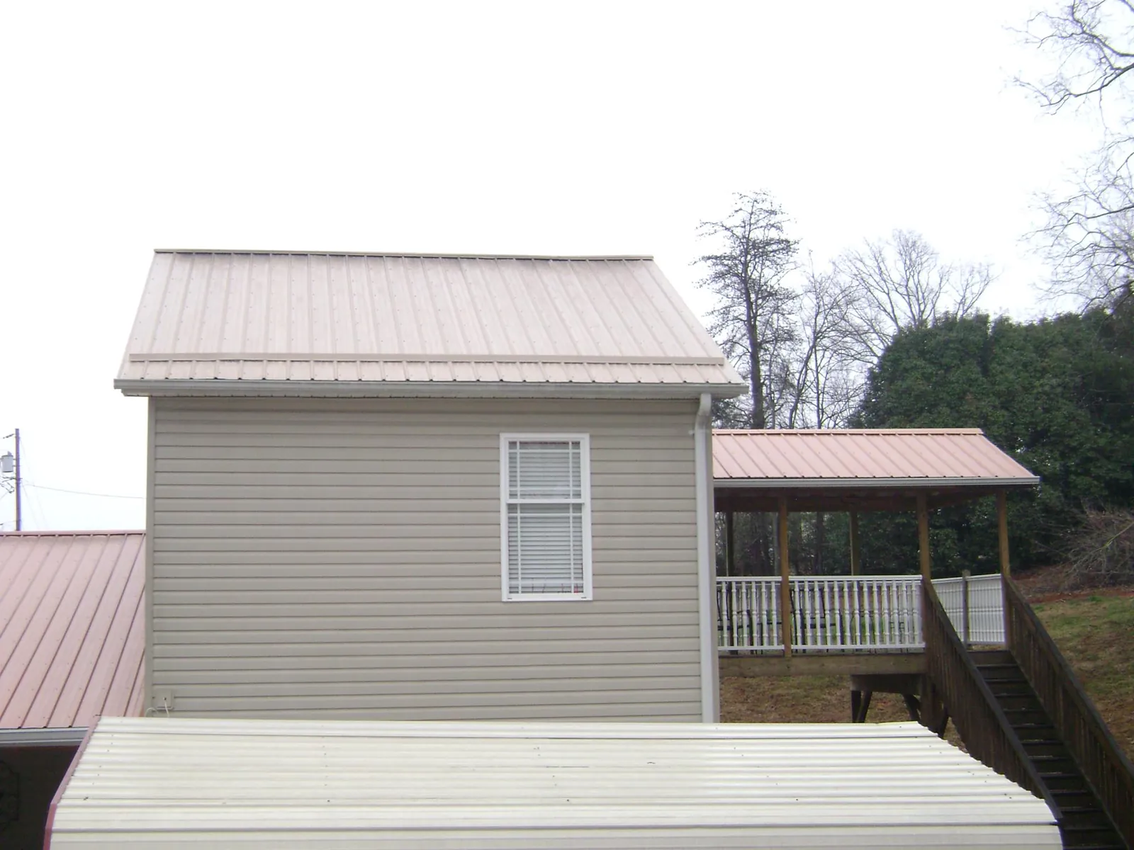 Tan metal roofs on a two story addition and attached porch, from a Roof Replacement job in Tuskegee Institute
