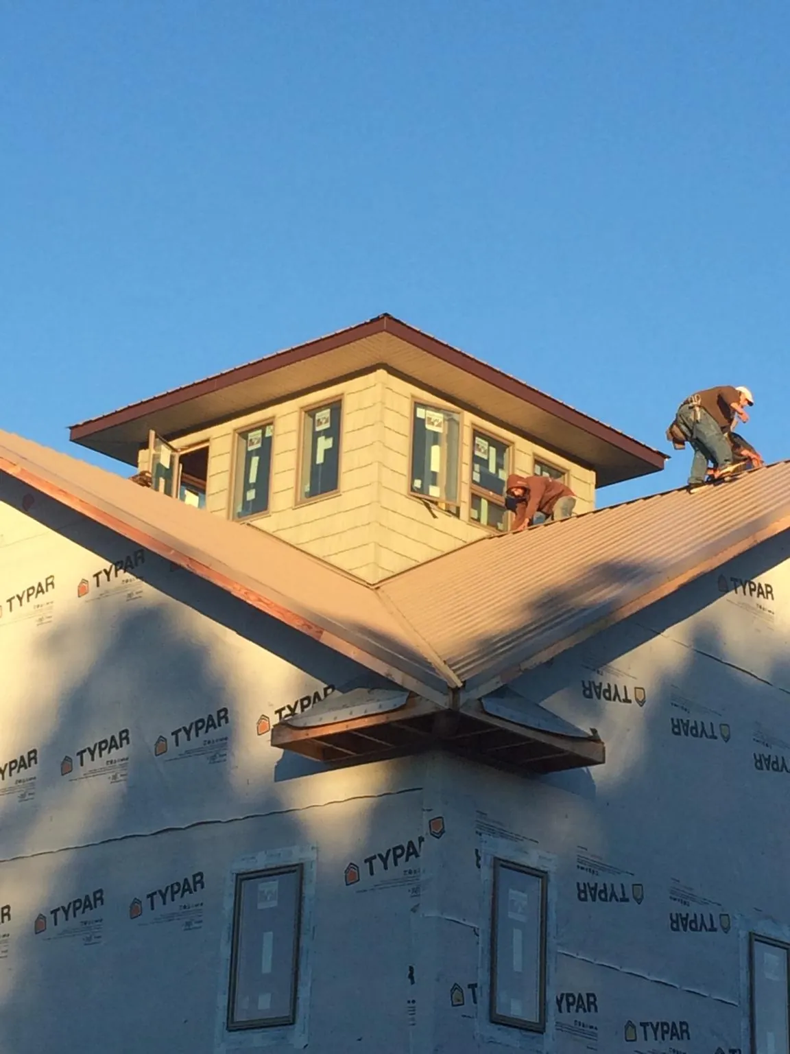Roofers working around a rooftop cupola on a new metal roof at sunset — Roof Waterproofing in Tuskegee Institute by Roofing Brothers